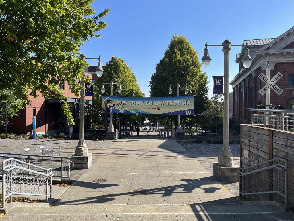 Daytime setting photo of an outdoor plaza displaying a WELCOME banner on the UW Tacoma campus.